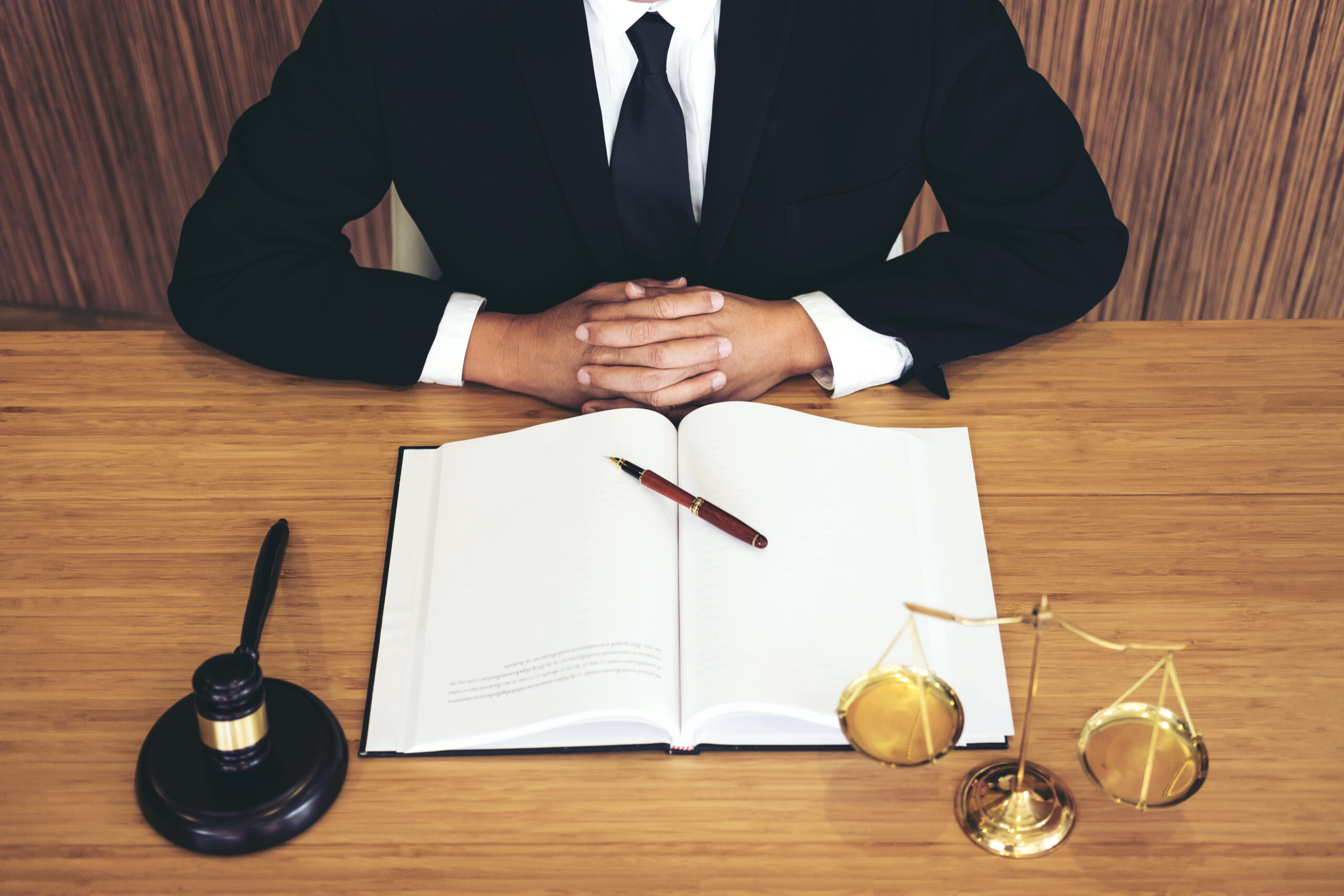 A Lawyer holding his hand on a table with a book and pen